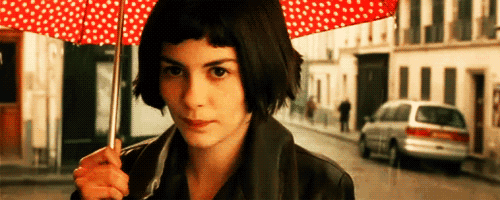a woman is holding a red polka dot umbrella on a street