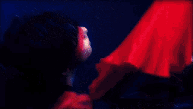 a woman in a red dress is standing in a dark room