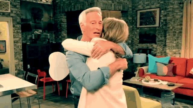 a man and woman hugging in a living room with a red couch