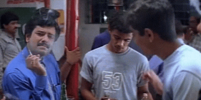 a man is smoking a cigarette while standing next to another man wearing a shirt that says 53 .