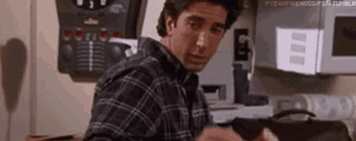 a man in a plaid shirt is sitting in a kitchen with a microwave .