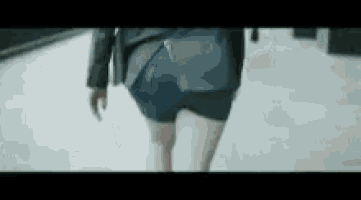 a woman wearing shorts and a jacket is walking down a street .