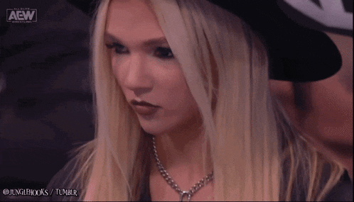 a blonde woman wearing a black hat with the aew logo on the bottom right