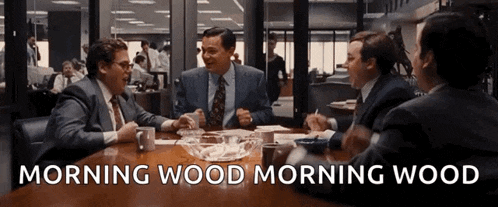 a group of men are sitting around a table and the words morning wood morning wood are visible