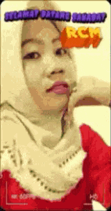 a woman wearing a white hijab and a red shirt is looking at the camera