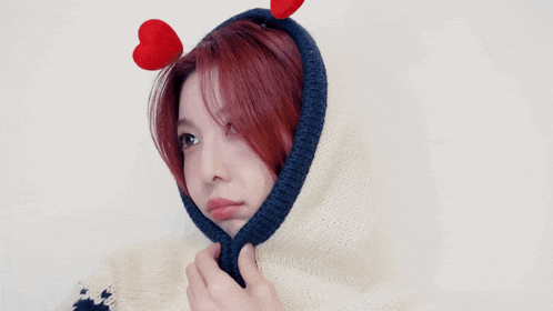 a woman with red hair is wearing a sweater with a hood and heart ears