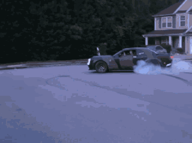 a car with smoke coming out of the tires is driving down a street