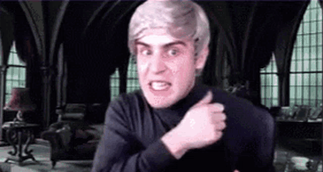 a man with a wig on is giving a thumbs up in a room .