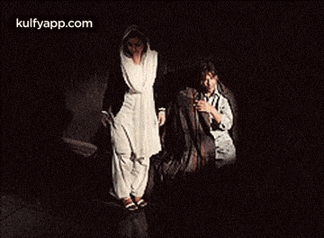 a man and a woman are sitting on a bench in a dark room .
