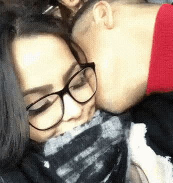 a man and a woman wearing glasses are kissing each other .