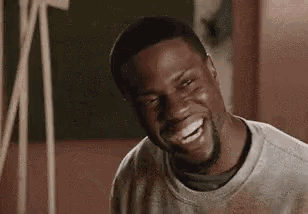 a man with a beard is laughing while wearing a white shirt .