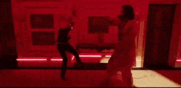a man with a beard is dancing in a red room with a crowd .