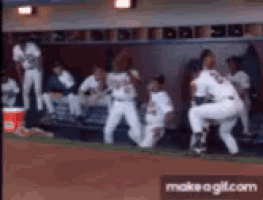 a group of baseball players are in a dugout and one of them is wearing a jersey with the number 14 on it