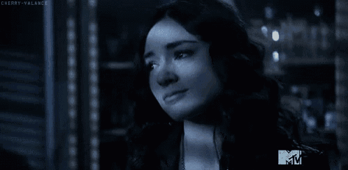a close up of a woman 's face in a dark room with a mtv logo in the background .