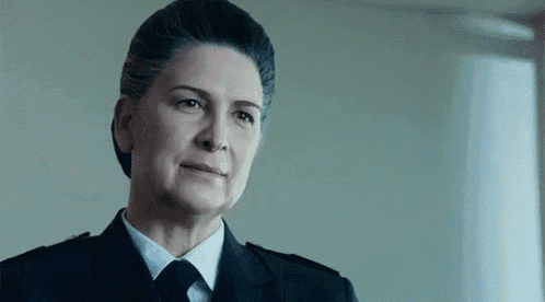 a woman in a suit and tie is looking at the camera .