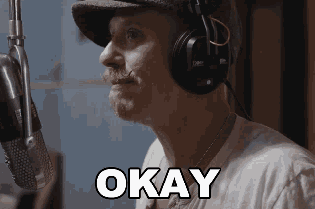 a man wearing a hat and headphones says okay in front of a microphone