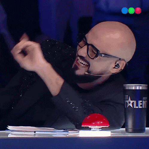 a man wearing glasses and a microphone is sitting at a table with a cup that says talent on it