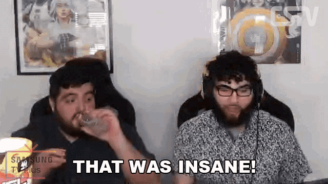 two men are sitting next to each other in a room and one of them is drinking water .