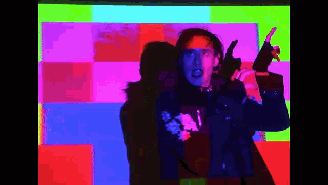 a man is holding a gun in front of a colorful backdrop