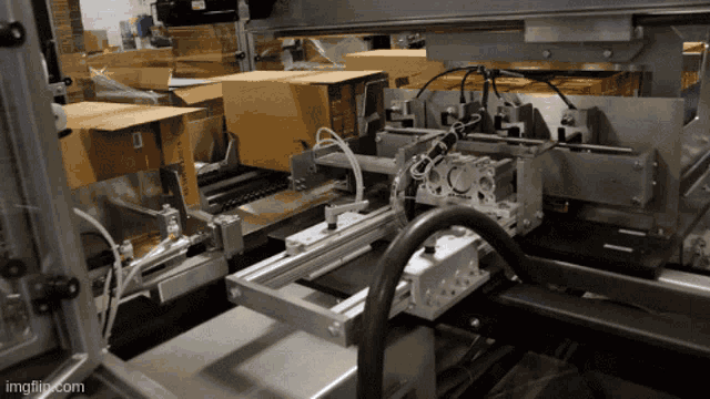 cardboard boxes are being loaded into a machine with the url imgflip.com at the bottom