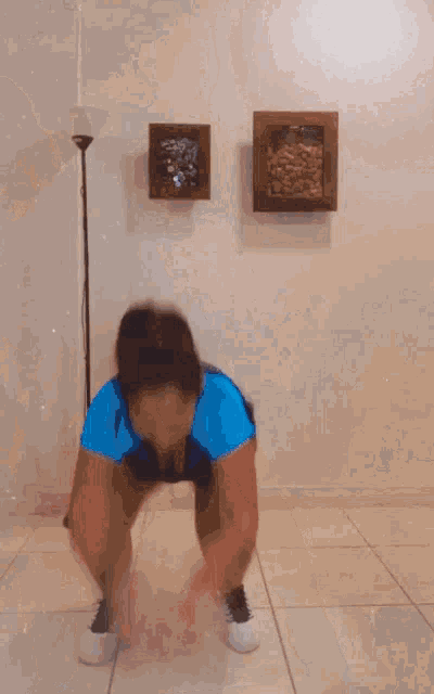 a man in a blue shirt is doing a handstand in a room