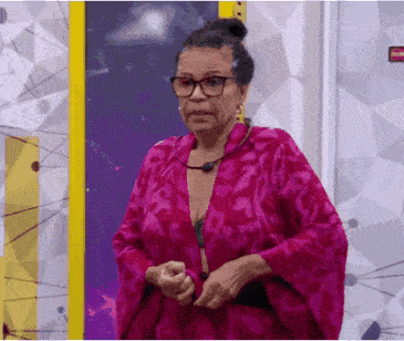 a woman wearing glasses and a pink robe stands in front of a wall