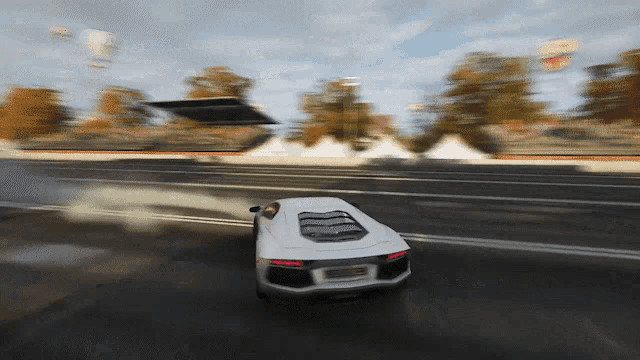 a white car is driving down a road with smoke coming out of it