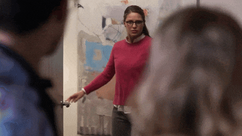 a woman in a red sweater is standing in front of a wall with a map on it