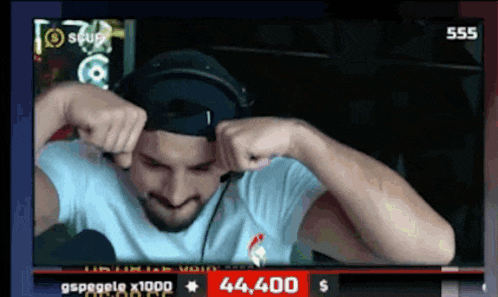 a man wearing headphones and a hat is playing a video game with the number 44440 on the screen
