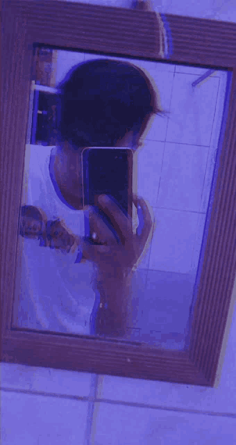 a man is taking a selfie in a mirror with a purple background