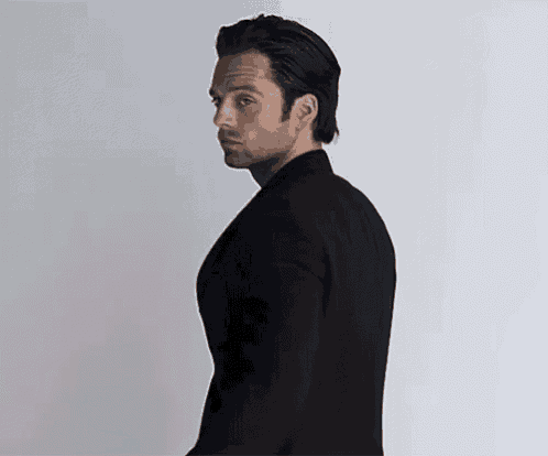 a man in a black suit is looking over his shoulder .