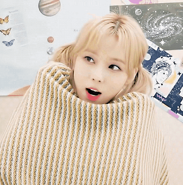 a girl with blonde hair is wearing a sweater and smiling