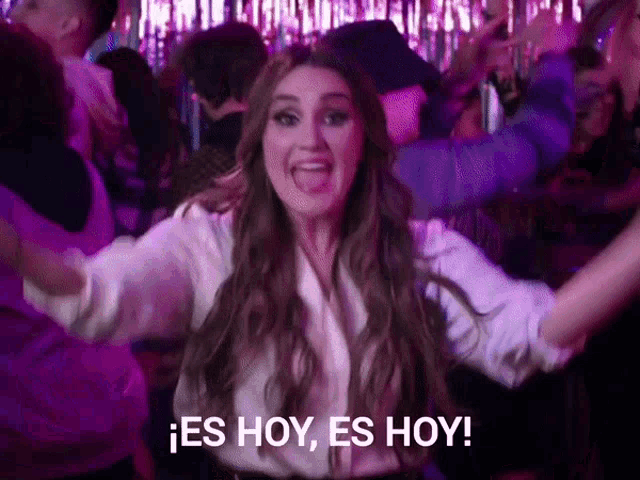 a woman in a white shirt is dancing in a crowd and says es hoy es hoy