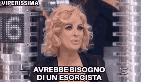 a woman with blonde hair is sitting in front of a sign that says ' viperissima ' on it