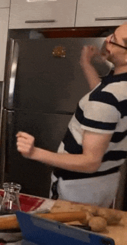 a man in a striped shirt is standing in front of a fridge