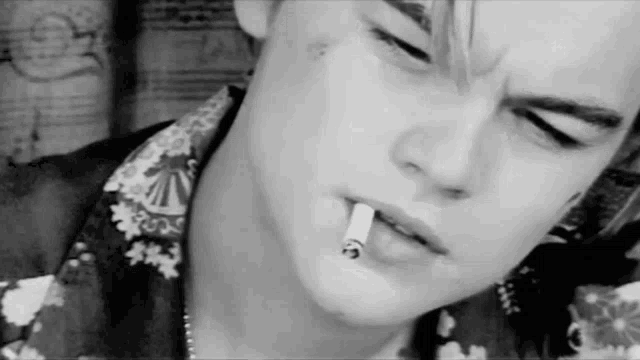 a black and white photo of a man smoking a cigarette in his mouth .