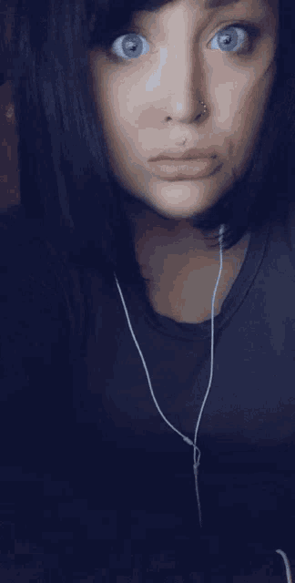 a woman with a nose ring is wearing earphones