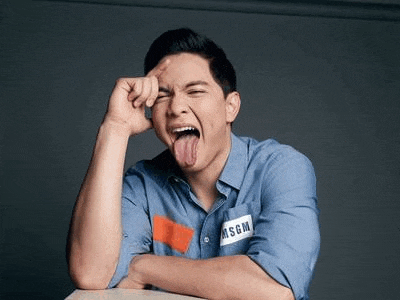 a man in a blue shirt is sticking his tongue out and making a funny face .