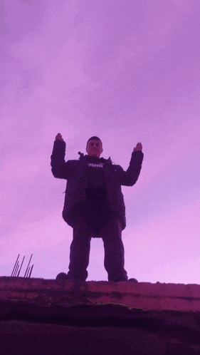 a man wearing a black jacket with the word prison on it stands in front of a purple sky