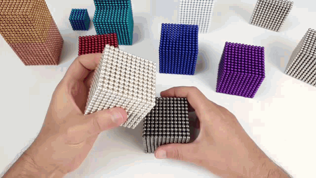 a person is playing with a bunch of different colored magnetic balls