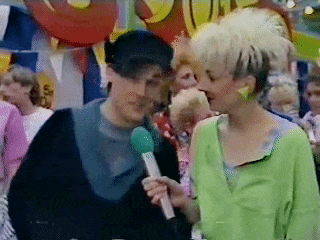 a woman in a green shirt is holding a microphone and talking to another woman