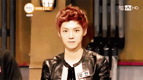 a young man with red hair is wearing a leather jacket .