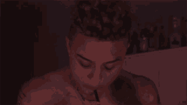 a shirtless man with curly hair and a tattoo on his chest is eating something .