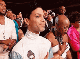 a man in a white turtleneck stands in a crowd