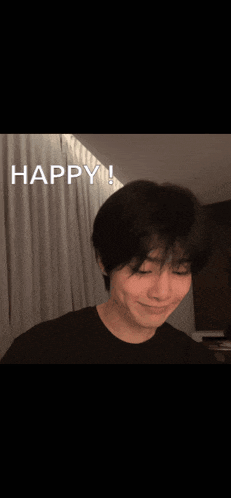a young man is smiling in front of a white curtain with the words happy written on it