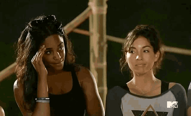 two women are standing next to each other in front of a tv screen that says mtv on it