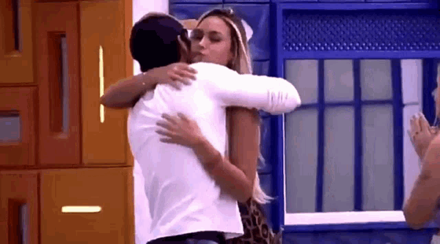 a man and a woman are hugging each other in a room in front of a window .