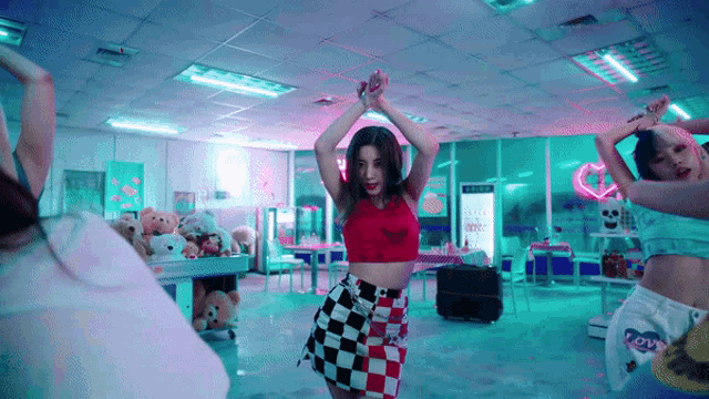 a woman wearing a red crop top and a checkered skirt is dancing in a room