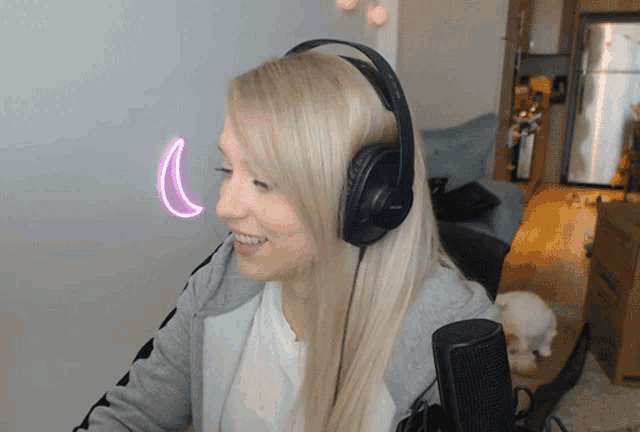 a woman wearing headphones is smiling with a pink crescent moon in the background