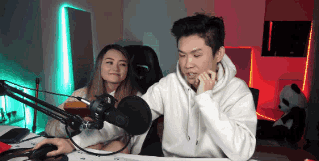 a man and a woman are sitting in front of a microphone in a room